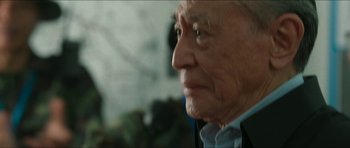 Movie still from “Cave Rescue” (2022), directed by Tom Waller – An old man with a beard looking to his left; Close Up shot, Over the shoulder angle