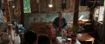 Movie still from “Cave Rescue” (2022), directed by Tom Waller – A man standing in front of a group of people in a room; Medium shot, Over the shoulder angle