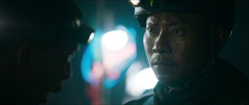 Movie still from “Cave Rescue” (2022), directed by Tom Waller – A person wearing a hard hat; Close Up shot, Over the shoulder angle