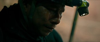 Movie still from “Cave Rescue” (2022), directed by Tom Waller – A person wearing a helmet; Close Up shot, High angle
