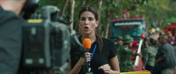 Movie still from “Cave Rescue” (2022), directed by Tom Waller – A woman is holding a microphone while standing in front of a video camera; Close Up shot, Over the shoulder angle
