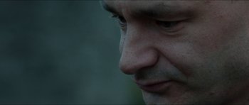 Movie still from “Cave Rescue” (2022), directed by Tom Waller – A man's face with a blurry background; Extreme Close Up shot, Low angle