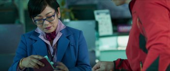Movie still from “Cave Rescue” (2022), directed by Tom Waller – A woman in a blue jacket and a red tie; Medium shot, Over the shoulder angle