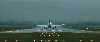 Movie still from “Cave Rescue” (2022), directed by Tom Waller – An airplane taking off from an airport runway at night; Extreme Wide shot, Low angle