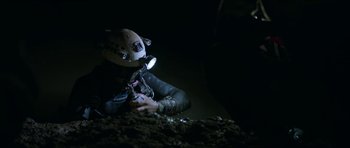 Movie still from “Cave Rescue” (2022), directed by Tom Waller – A person in a helmet is sitting in the dark; Wide shot, Overhead angle