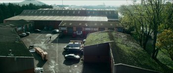 Movie still from “Cave Rescue” (2022), directed by Tom Waller – An aerial view of a parking lot with cars parked in front of it; Extreme Wide shot, High angle