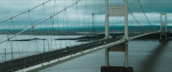 Movie still from “Cave Rescue” (2022), directed by Tom Waller – A view of a bridge from across the river; Extreme Wide shot, High angle