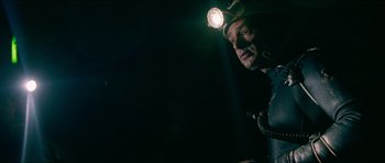 Movie still from “Cave Rescue” (2022), directed by Tom Waller – A man wearing a hard hat with a light on his head; Medium shot, Low angle