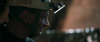 Movie still from “Cave Rescue” (2022), directed by Tom Waller – A person wearing a helmet; Close Up shot, Over the shoulder angle
