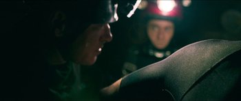 Movie still from “Cave Rescue” (2022), directed by Tom Waller – A man in a motorcycle helmet looking at another man in a motorcycle helmet; Close Up shot, Over the shoulder angle