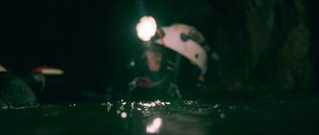 Movie still from “Cave Rescue” (2022), directed by Tom Waller – A blurry image of a person holding a skateboard; Wide shot, Overhead angle