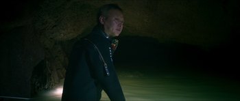 Movie still from “Cave Rescue” (2022), directed by Tom Waller – A man standing in a cave at night; Medium shot, Low angle