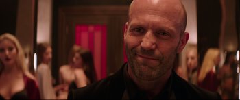 Movie still from “Fast & Furious Presents: Hobbs & Shaw” (2019), directed by David Leitch – A man with a shaved head is smiling for the camera; Close Up shot, Over the shoulder angle