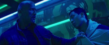 Movie still from “Fast & Furious Presents: Hobbs & Shaw” (2019), directed by David Leitch – Two men are standing in a room lit up by neon lights; Close Up shot, Over the shoulder angle