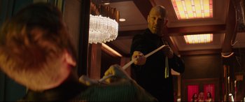 Movie still from “Fast & Furious Presents: Hobbs & Shaw” (2019), directed by David Leitch – A man is playing the drums in a room; Medium shot, Over the shoulder angle