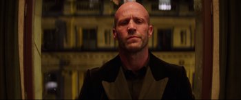 Movie still from “Fast & Furious Presents: Hobbs & Shaw” (2019), directed by David Leitch – A bald man wearing a black jacket and a black shirt; Close Up shot, Low angle