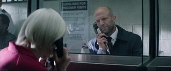 Movie still from “Fast & Furious Presents: Hobbs & Shaw” (2019), directed by David Leitch – A man in a suit and tie holding a phone to his ear; Close Up shot, Over the shoulder angle