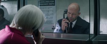 Movie still from “Fast & Furious Presents: Hobbs & Shaw” (2019), directed by David Leitch – A man in a suit and tie talking on a phone; Medium shot, Over the shoulder angle
