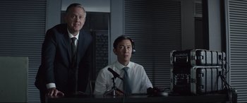 Movie still from “Fast & Furious Presents: Hobbs & Shaw” (2019), directed by David Leitch – Two men in suits and ties sitting in front of microphones in a room; Medium shot, Low angle