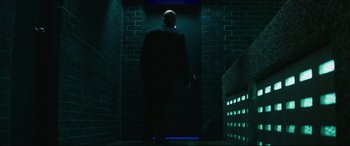 Movie still from “Fast & Furious Presents: Hobbs & Shaw” (2019), directed by David Leitch – A man in a black suit is walking down a dark hallway; Wide shot, Low angle