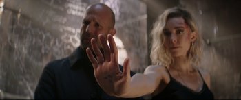 Movie still from “Fast & Furious Presents: Hobbs & Shaw” (2019), directed by David Leitch – A man and a woman standing next to each other holding up their hands; Close Up shot, Over the shoulder angle