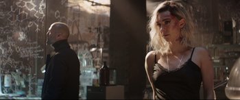 Movie still from “Fast & Furious Presents: Hobbs & Shaw” (2019), directed by David Leitch – A woman in a black top is posing for a picture; Medium shot, Over the shoulder angle