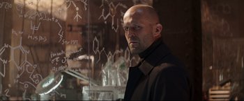 Movie still from “Fast & Furious Presents: Hobbs & Shaw” (2019), directed by David Leitch – A bald man with a goatee standing in front of a glass wall; Close Up shot, Over the shoulder angle