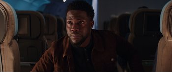 Movie still from “Fast & Furious Presents: Hobbs & Shaw” (2019), directed by David Leitch – A person wearing a brown jacket; Close Up shot, Over the shoulder angle