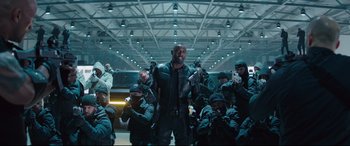 Movie still from “Fast & Furious Presents: Hobbs & Shaw” (2019), directed by David Leitch – A group of men in black suits and masks; Wide shot, Low angle