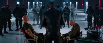 Movie still from “Fast & Furious Presents: Hobbs & Shaw” (2019), directed by David Leitch – A group of men standing next to each other in a room; Medium shot, Over the shoulder angle