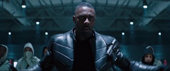 Movie still from “Fast & Furious Presents: Hobbs & Shaw” (2019), directed by David Leitch – A man in a leather jacket holding a gun in his hand; Medium shot, Low angle