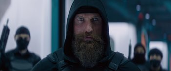Movie still from “Fast & Furious Presents: Hobbs & Shaw” (2019), directed by David Leitch – A man with a long beard wearing a black hooded jacket; Close Up shot, Low angle