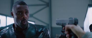 Movie still from “Fast & Furious Presents: Hobbs & Shaw” (2019), directed by David Leitch – A person with a gun in a room; Close Up shot, Over the shoulder angle