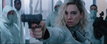 Movie still from “Fast & Furious Presents: Hobbs & Shaw” (2019), directed by David Leitch – A woman holding a gun while standing next to a window; Close Up shot, Over the shoulder angle