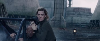 Movie still from “Fast & Furious Presents: Hobbs & Shaw” (2019), directed by David Leitch – A woman holding a video camera while standing next to a man; Medium shot, Low angle