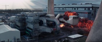Movie still from “Fast & Furious Presents: Hobbs & Shaw” (2019), directed by David Leitch – An industrial building with a large amount of smoke coming from it; Extreme Wide shot, High angle