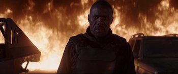 Movie still from “Fast & Furious Presents: Hobbs & Shaw” (2019), directed by David Leitch – A man standing in front of a burning fire; Medium shot, Low angle