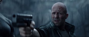 Movie still from “Fast & Furious Presents: Hobbs & Shaw” (2019), directed by David Leitch – A bald man holding a gun in the rain; Close Up shot, Low angle