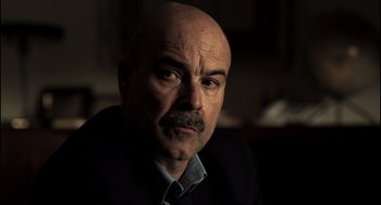 Movie still from “Cell 211” (2009), directed by Daniel Monzón – A bald man with a mustache is looking at the camera; Close Up shot, Over the shoulder angle