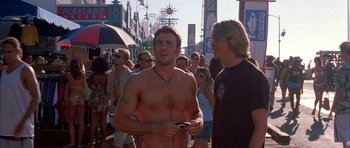 Movie still from “Cellular” (2004), directed by David R. Ellis – A shirtless man standing next to a crowd of onlookers; Medium shot, Low angle