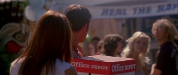 Movie still from “Cellular” (2004), directed by David R. Ellis – A man sitting in front of a box of office supplies; Medium shot, Over the shoulder angle