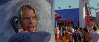 Movie still from “Cellular” (2004), directed by David R. Ellis – A man with a long blonde hair and a beard is sticking his head through a stuffed animal; Close Up shot, Over the shoulder angle