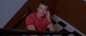 Movie still from “Cellular” (2004), directed by David R. Ellis – A man sitting on the stairs talking on a cell phone; Medium shot, High angle