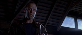 Movie still from “Cellular” (2004), directed by David R. Ellis – A bald man holding a cell phone while wearing a jacket; Close Up shot, Low angle