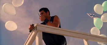 Movie still from “Cellular” (2004), directed by David R. Ellis – A man standing on top of a white rail holding a cell phone to his ear; Medium shot, Low angle