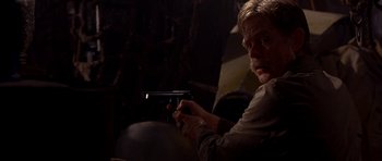 Movie still from “Cellular” (2004), directed by David R. Ellis – A man holding a gun in a dimly - lit room; Close Up shot, Over the shoulder angle