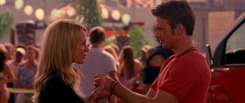 Movie still from “Cellular” (2004), directed by David R. Ellis – A man and a woman holding hands in front of a crowd of onlookers; Close Up shot, Over the shoulder angle