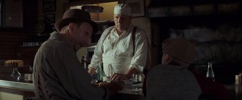 Movie still from “Changeling” (2008), directed by Clint Eastwood – A man in a chef's hat standing at a table with two other men; Medium shot, Over the shoulder angle