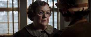 Movie still from “Changeling” (2008), directed by Clint Eastwood – An older woman wearing glasses looking at the camera; Close Up shot, Over the shoulder angle