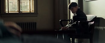 Movie still from “Changeling” (2008), directed by Clint Eastwood – A person sitting in a chair looking at a phone; Medium shot, Over the shoulder angle